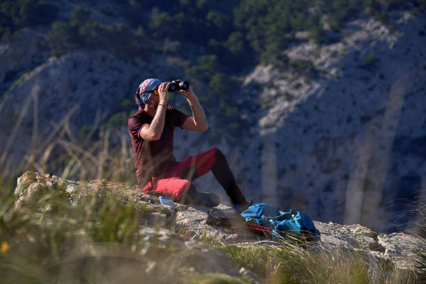 istock Male tourist sitting on rock with binoculars 1839652227