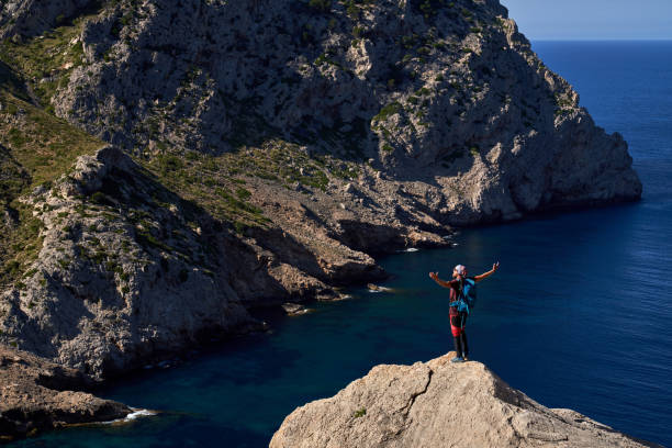 istock Man standing on rocky cliff and spreading arms 1839658017