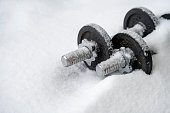 Sport in winter concept. Dumbbells covered by snow