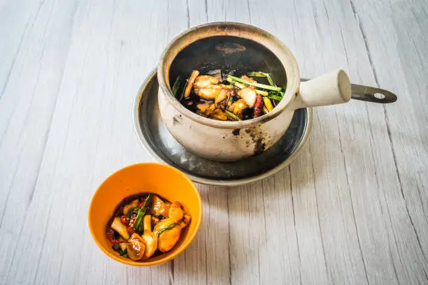 Stir fry frog leg with spring onions and dried reed chilli and served in a claypot