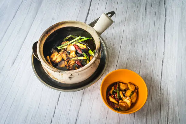 Stir fry frog leg with spring onions and dried reed chilli and served in a claypot