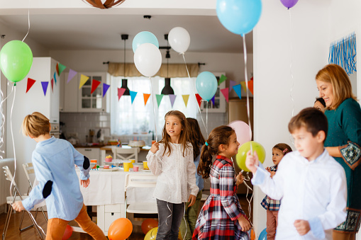 Group of children playing with balloons on a indoors Birthday party