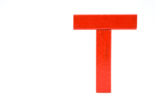 Red wooden brick, letter T, standing isolated on a white background.