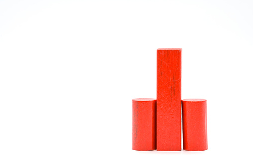 Red wooden building block standing with cylinders on the left and right, isolated on a white background. Symbolic penis and testicles