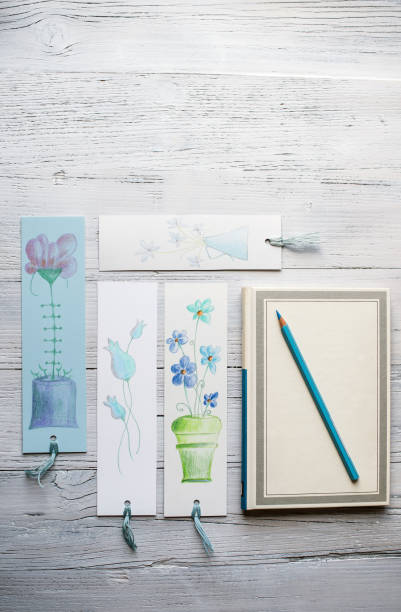 Flat Lay Concept of Notebook with Blooming Bookmarks on White Wooden Background