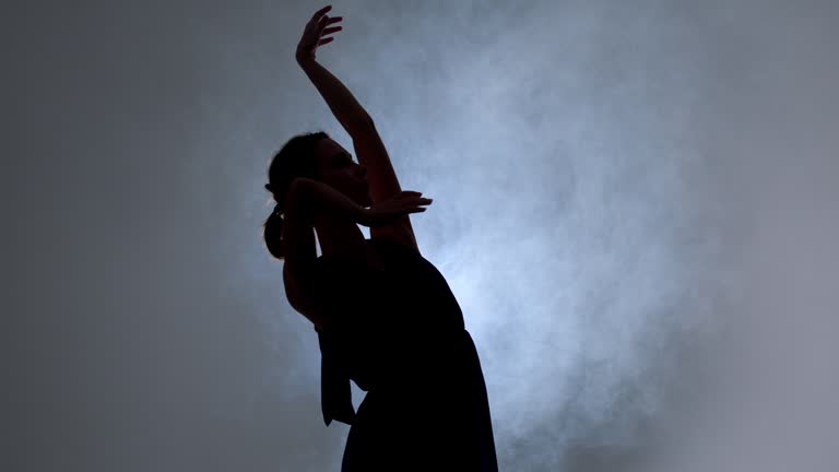 Graceful hard-working ballerina dancing in blue dress in the studio