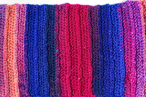 Close-up of abstract crochet pattern of home made clothing made of colorful merino wool against white background. Photo taken December 8th, 2023, Zurich, Switzerland.