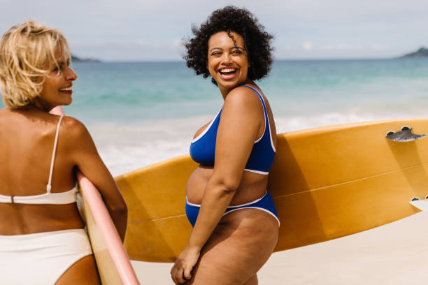 istock Two women in bikinis going for a surf at the beach 1839764495