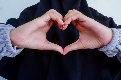 Muslima woman showing heart sign with hand gesture