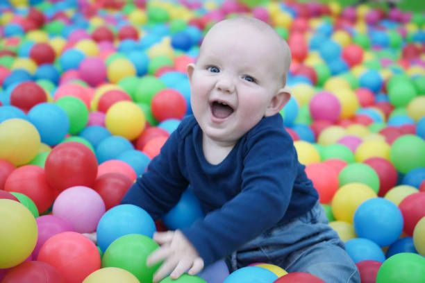 istock A satisfied baby sits among bright multi-colored balls and smiles joyfully 1839800281