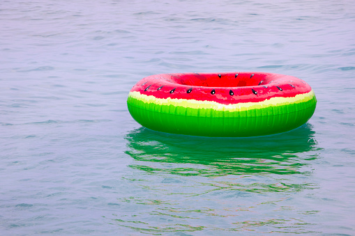 swimming ring with a watermelon pattern on the surface of the water in the sea. Marine family vacations and holidays
