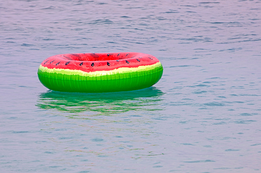 swimming ring with a watermelon pattern on the surface of the water in the sea. Marine family vacations and holidays