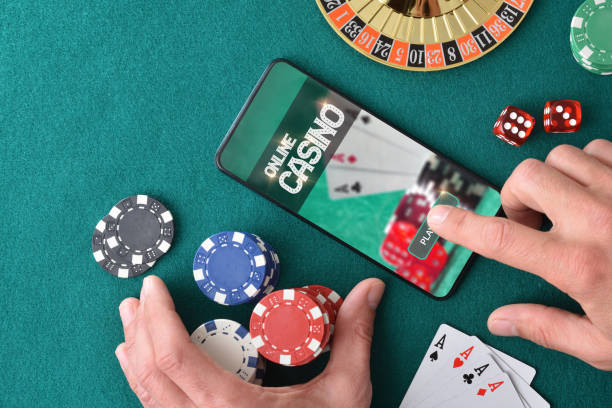 Online game app on tablet on game table with objects Online casino player entering app to play with hand pressing on smartphone screen on green felt gaming table with betting chips and casino game objects. Top view. mobile casino games stock pictures, royalty-free photos & images