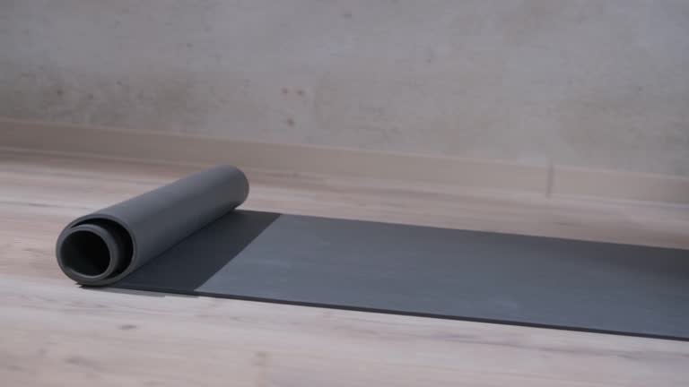 A man rolls a yoga mat in the studio, close-up.