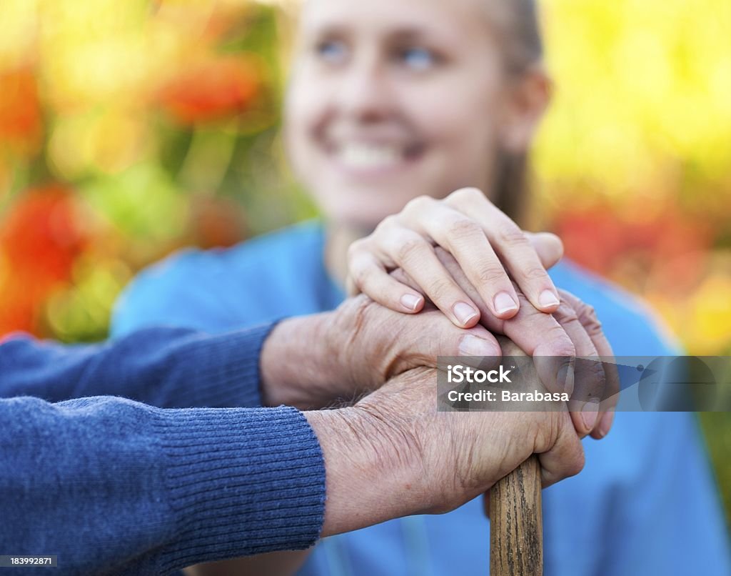 Young woman doctor helping a senior Young female doctor holding his patient hand. Holding Stock Photo