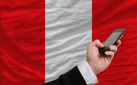 man holding cell phone in front national flag of peru symbolizing mobile communication and telecommunication