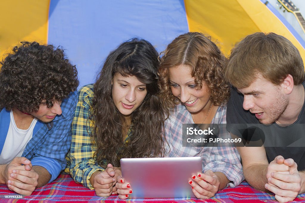 Gruppo di amici il campeggio al fiume lettura su digital tablet - Foto stock royalty-free di Adulto
