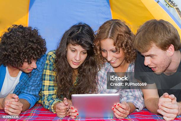 Grupo De Amigos De Acampamento Em Rio Leitura Sobre Tablet Digital - Fotografias de stock e mais imagens de 20-29 Anos