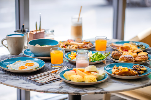 Sumptuous breakfast spread on table in bright cafe. Dining and cuisine.