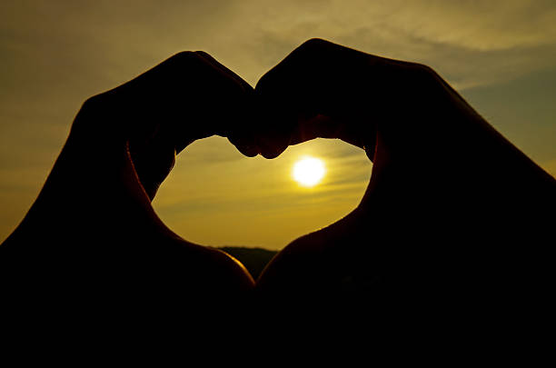 istock Heart silhouette by hand on sunrise background 183995661