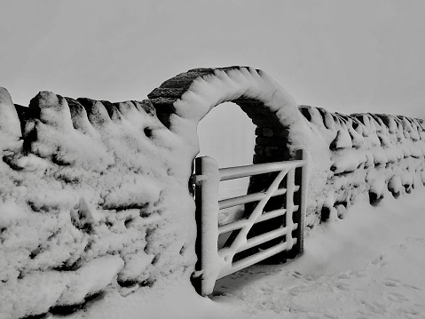 Snow covered stone wall archway and gate