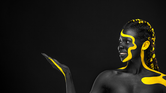 The Art Face. Black and yellow body paint on african woman. Abstract creative portrait. Copy space for your text