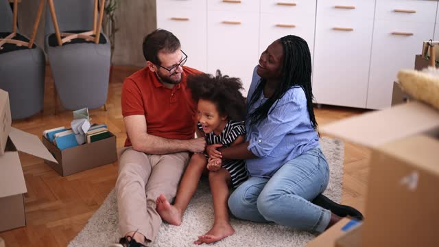 Multiracial Family Sitting On The Carpet Of Their New Apartment