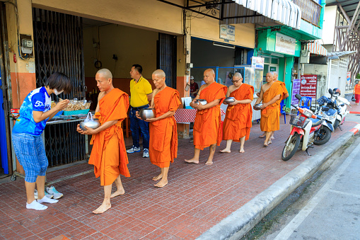 Lampang, Thailand - December 2, 2023: Thai Theravada Buddhist monks walking for morning alms in Nakhon Lampang, Thailand.