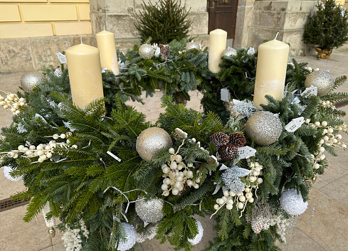 Two of four candles are burning for the second Advent on fir branches with Christmas decoration against a grey background, copy space, selected focus, narrow depth of field