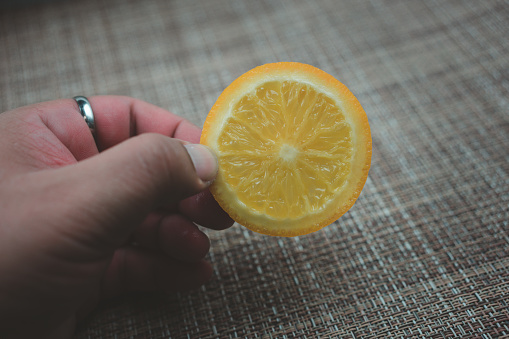 Closeup hand holding fresh slice lemon, contains a large amount of vitamins c