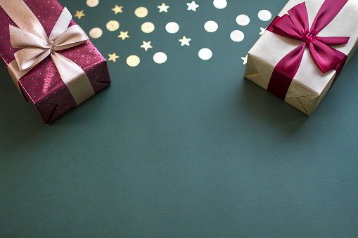 Flat lay Christmas composition with gift boxes and glitter on green background with copy space