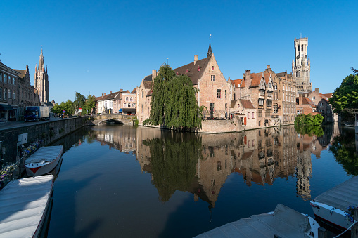 Bruges, Belgium - July 07, 2023: Famous Rosary Quay (Rozenhoedkaai) in the most popular waterway canal in the old town of the beautiful city of Brugge in Belgium at sunrise, with its historic facades
