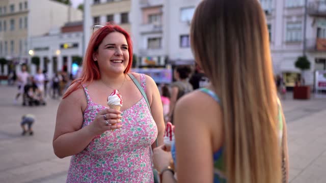 Two Female Friends Eating Ice Cream And Talking In The City