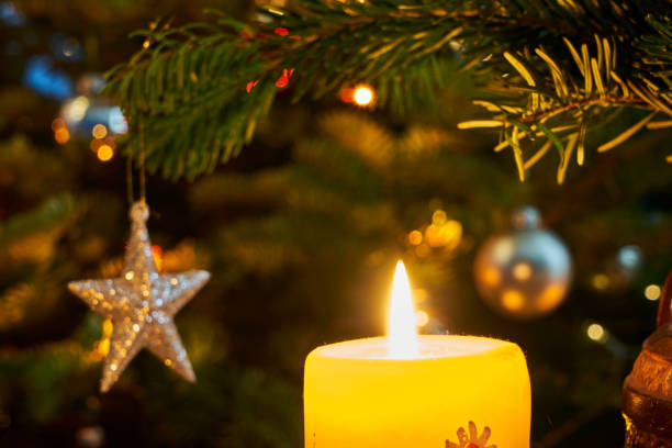 istock Candle flame and star-shaped Christmas decoration on the tree during Christmas 1840070968