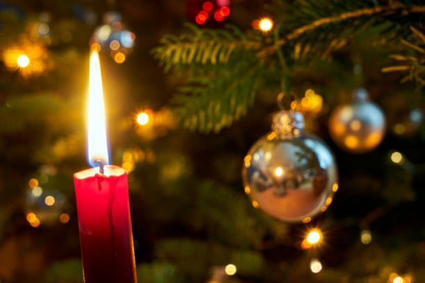 Candle flame and  Christmas decorations on the tree during Christmas, Poland
