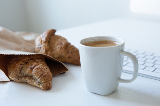 Morning background. Coffee with croissant and computer