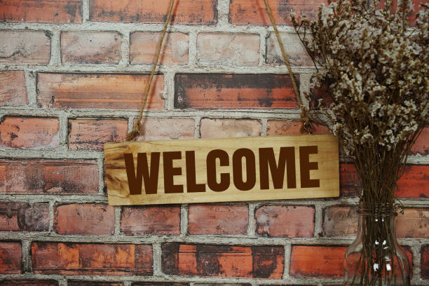 istock Welcome sign text message on wooden board hanging on old brick wall background 1840102308
