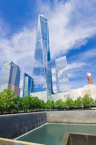 World Trade Center Towers, Pool with Waterfall of the 9/11 Memorial and Oculus Transportation Hub with Blue Sky in Background. The Pool is where the Footprints of the Twin Towers were and is Free for Public Viewing, New York City, NY, USA. Stitched Panoramic image. 3:2 Image Aspect Ratio. Canon EOS 6D (full frame sensor) DSLR and Canon EF 24-105mm F/4L IS lens.