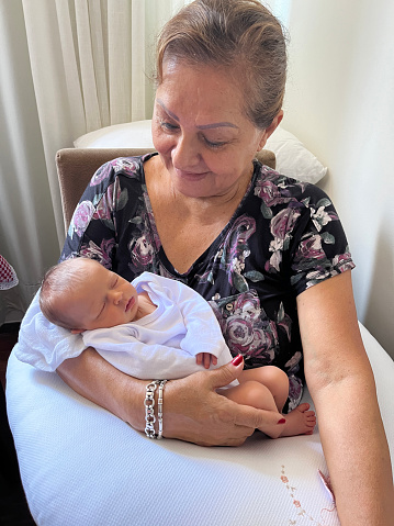 Week old baby girl in grandmother arms