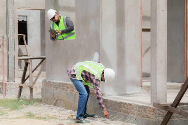 istock Two construction foreman workers examine inspect unfinished property site outdoor, Asian or Indian contractor man partnership and engineering project manager wearing reflection vest working together 1840137055
