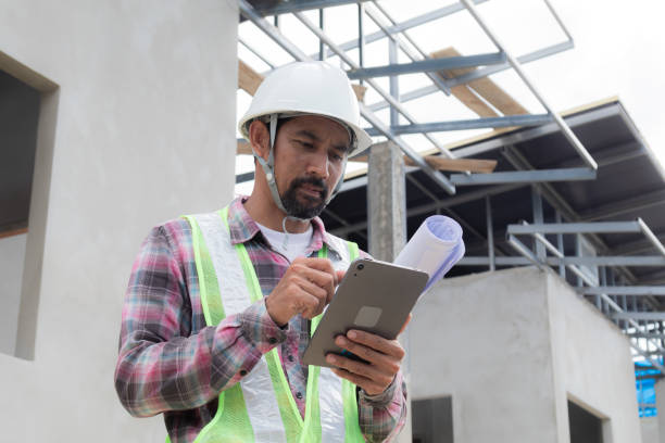 istock Asian or Indian foreman thoughtful wearing safety reflective vest at construction site holding blueprint paperwork looking Tablet technology searching, architect engineering middle-aged male working 1840141070