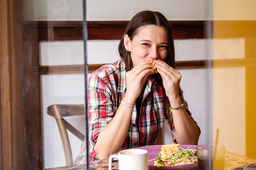 Woman making funny face while eating breakfast in cafe.
