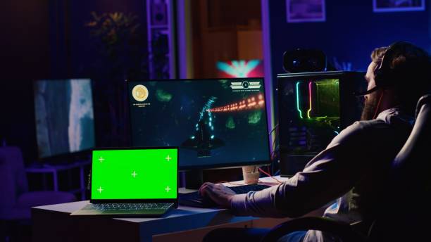 istock Green screen laptop next to man using gaming keyboard to play spaceship flying singleplayer game 1840249952