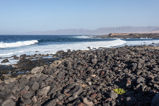 Coast of volcanic canary island Lanzarote at La Santa with Risco Famara in background