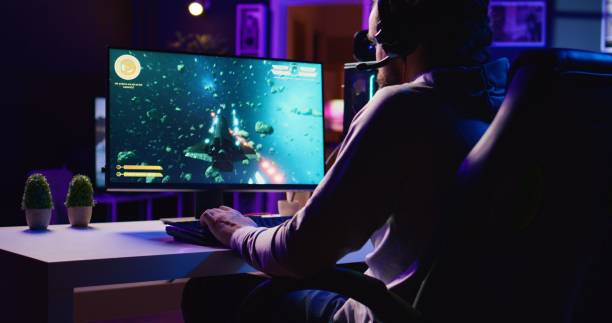 istock Man in dimly lit apartment playing singleplayer videogame with spaceship shooting 1840264951