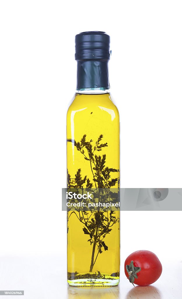 Olive oil in bottle Olive oil in glass bottle with herb inside and cherry tomato, closeup Canola Stock Photo