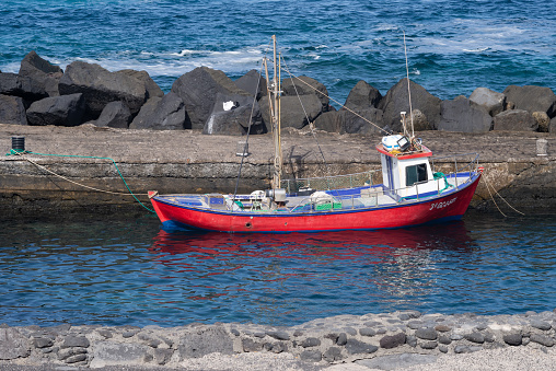Little red fishing boat moored up in the small harbour bassin of La Santa on canary island Lanzarote