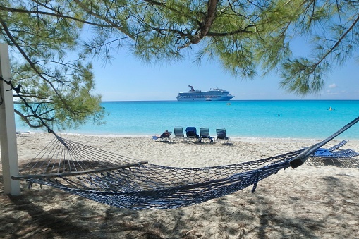Half Moon Key, Bahamas, Jan 2019: Shady beach hammock with  Cruise ship anchored off of private island in the Bahamas
