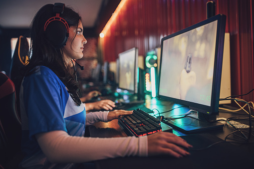Professional eSports Young Woman Gamer focused while playing video game with her team