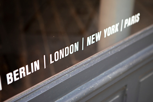 'Berlin, London, New York, Paris' painted on a shop or gallery window